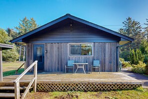 Une cabane en bois avec une véranda, deux chaises et une table.