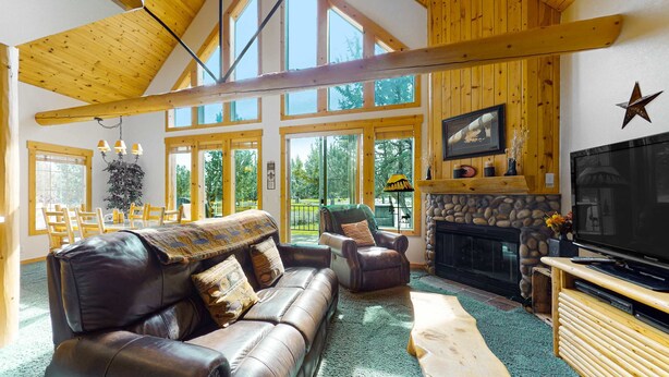 A spacious living room with a leather sofa, a wooden coffee table, and a stone fireplace. - Inviting chalet with private hot tub, grill, 3 pools, hot tub, gym, & tennis (Eagle Crest)