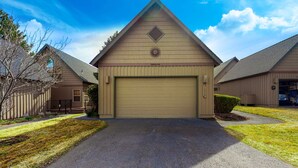 A residential building with a garage, a triangular roof, and a clear sky. - Inviting chalet with private hot tub, grill, 3 pools, hot tub, gym, & tennis (Eagle Crest)