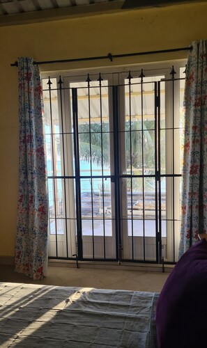 Quarto com cama, janela com grades e vista para o exterior.