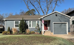 A residential house with a garage, a lawn, and a small tree.
