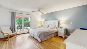 Ein Schlafzimmer mit Bett, Stuhl, Nachttisch, Lampe und Deckenventilator.