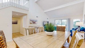 Un vaste espace de vie comprenant une table à manger, des chaises, une plante en pot et un canapé bleu.