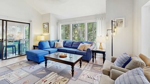 A living room with a blue sectional sofa, a coffee table, and a patterned rug. - Home with patio, golf views, close to beach and restaurants (Edisto Beach)