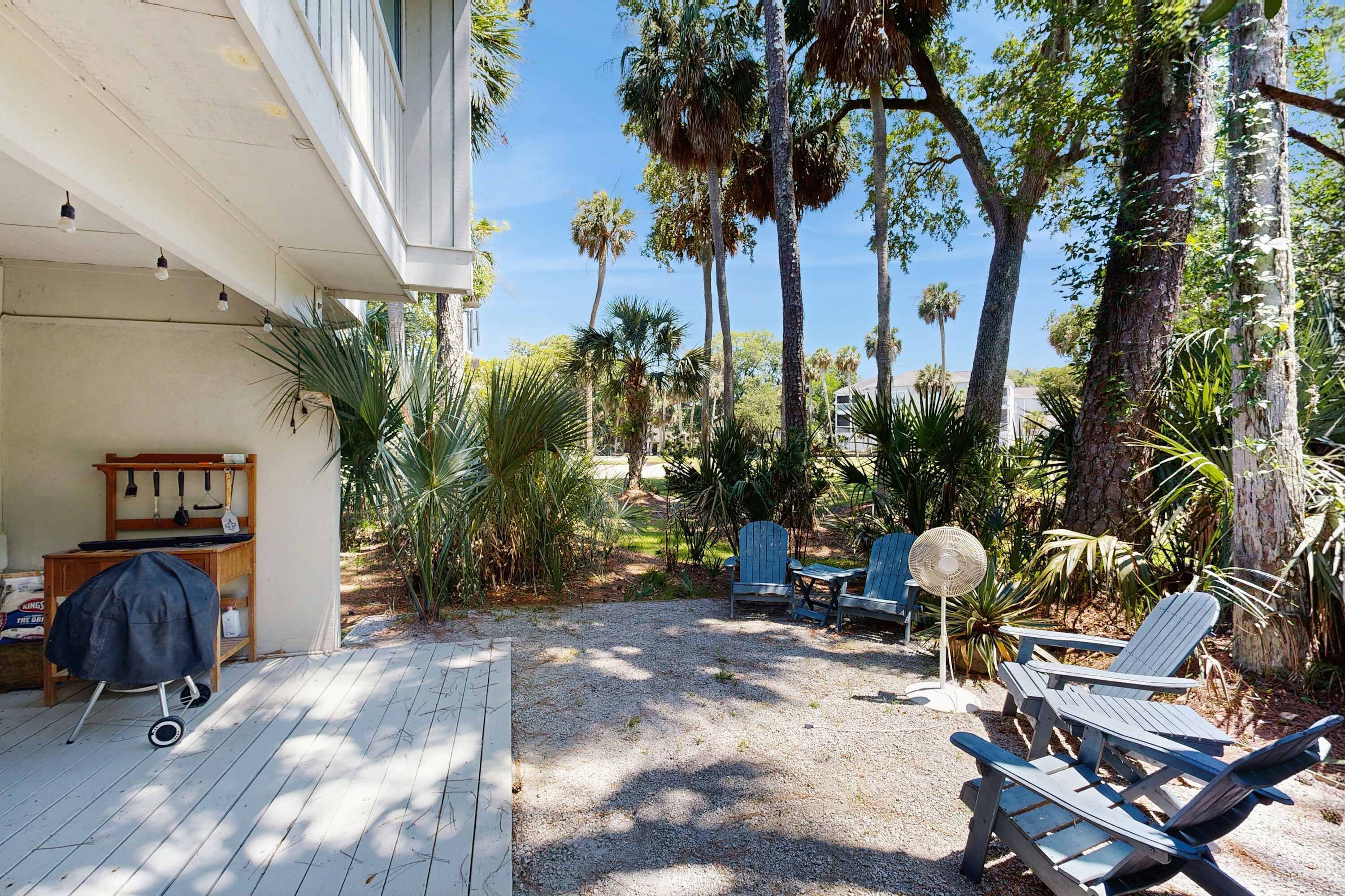 A covered patio with a grill, outdoor chairs, and a fan.