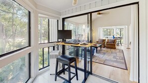 A modern interior with a glass partition, a desk with a computer, a chair, and a dining area with a table and chairs. - Home with patio, golf views, close to beach and restaurants (Edisto Beach)