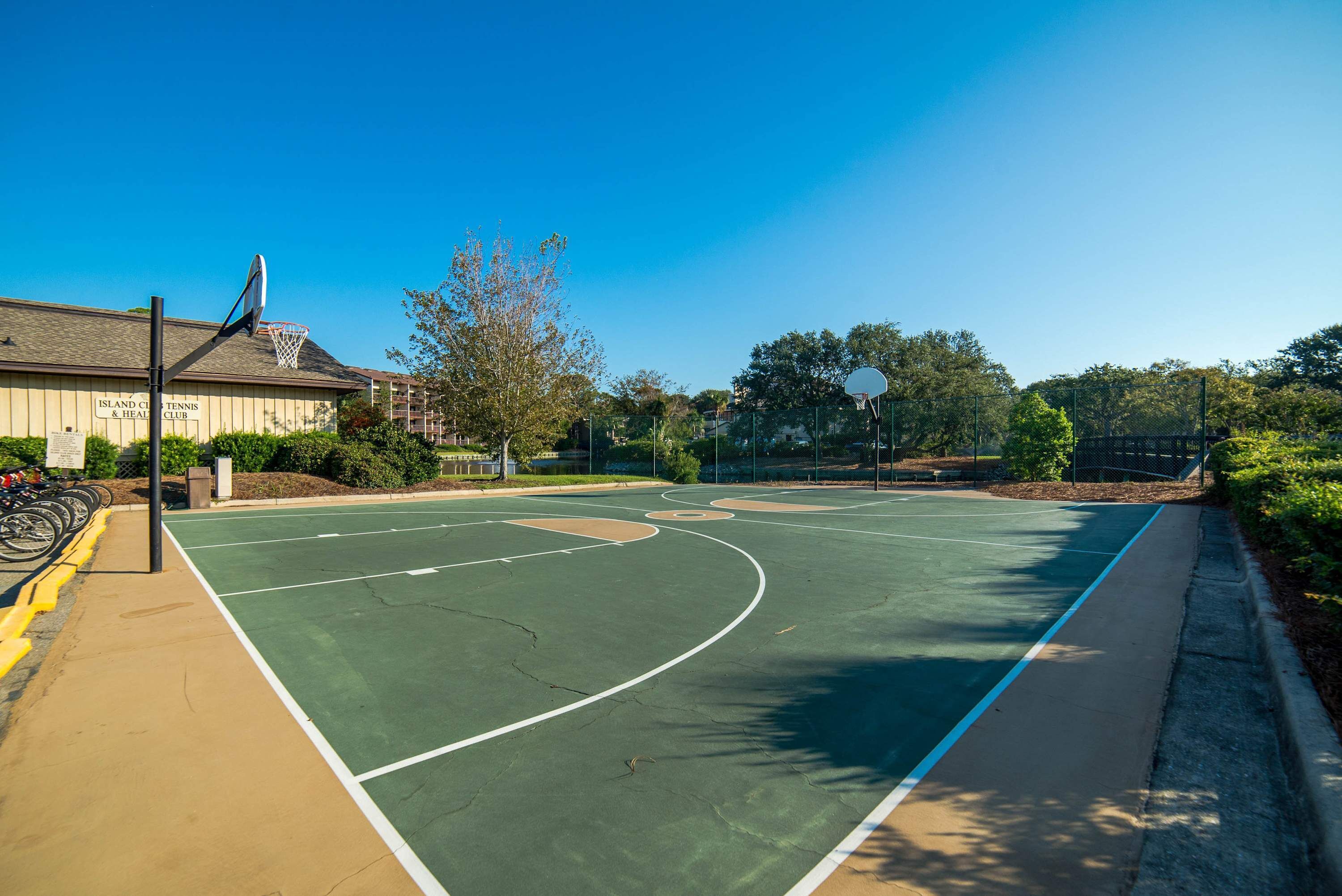 Ein Basketballplatz im Freien, im Hintergrund ein Gebäude mit der Aufschrift 'Island Club Tennis & Health Club'.