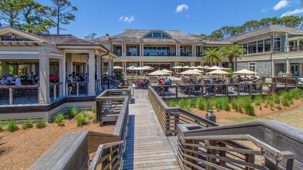 Ein Hotel direkt am Strand mit Außenbereich zum Essen, einer Holzpromenade und einem Poolbereich.