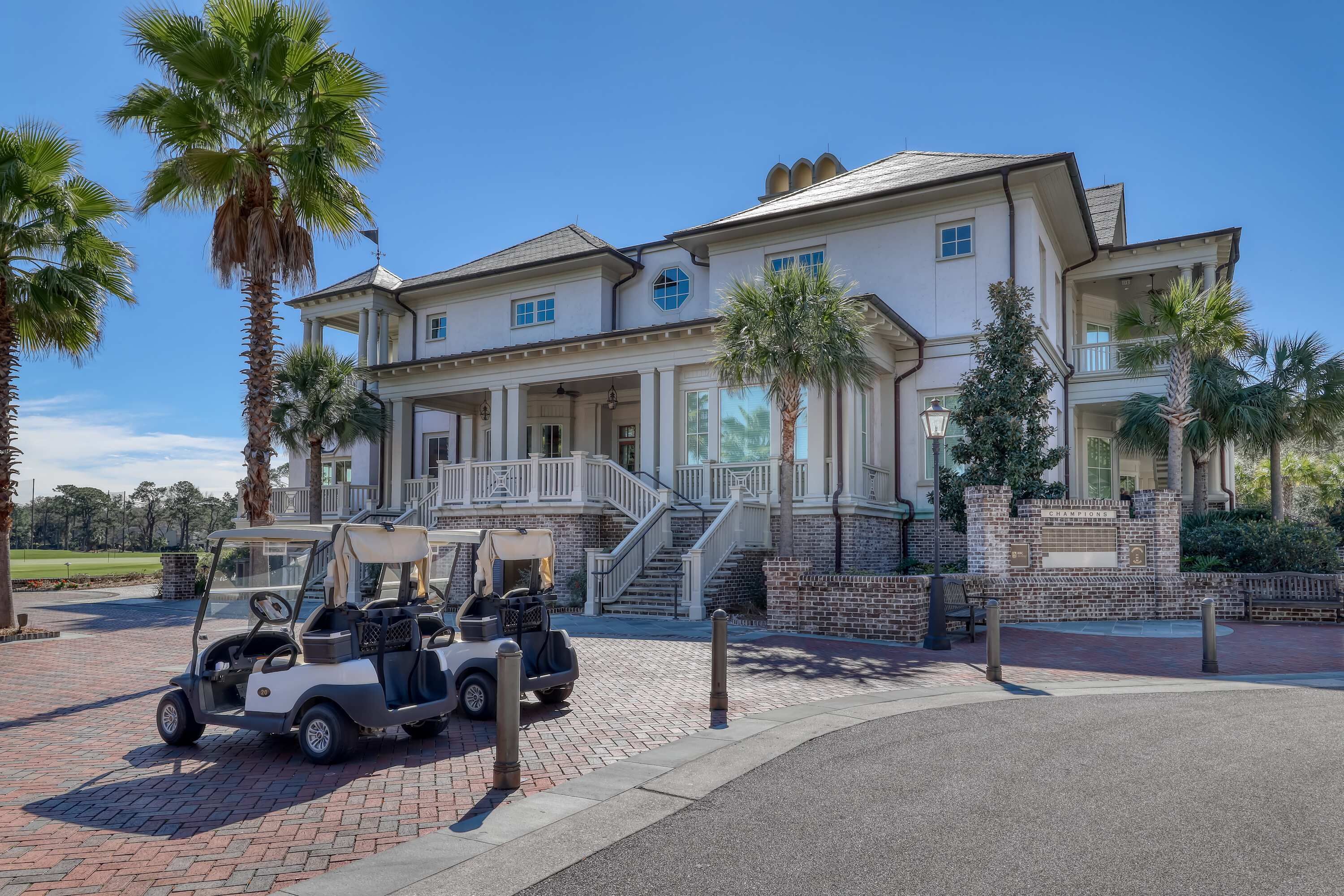 Un edificio grande, su due piani, con un portico, una scala e un golf cart parcheggiato davanti.