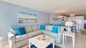 Un salon avec un canapé, une table basse et un tableau accroché au mur.