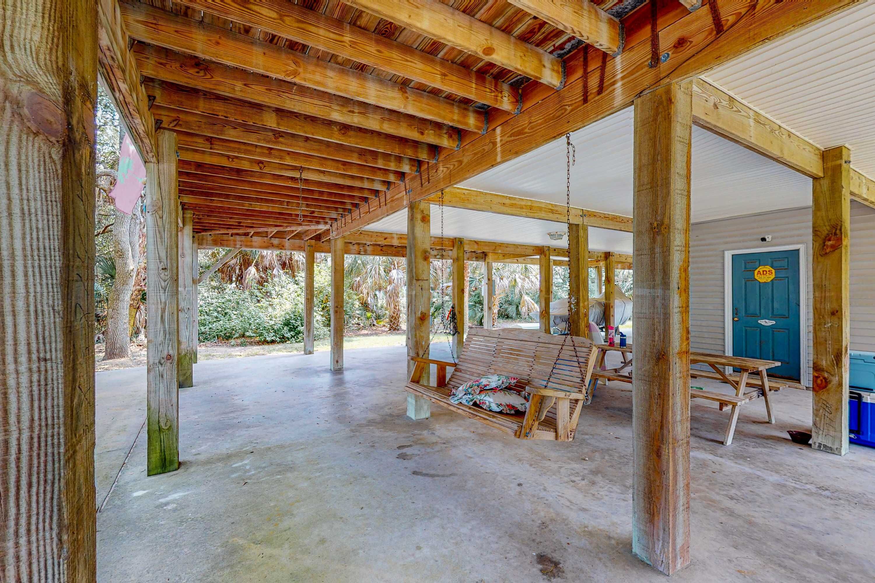 An open wooden structure with a swing, a picnic table, and a door marked 'ADS'.