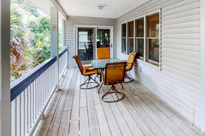 A covered porch with a table and chairs, a view of the outdoors, and a door leading to the interior. - Just Trippin' (Edisto Beach)