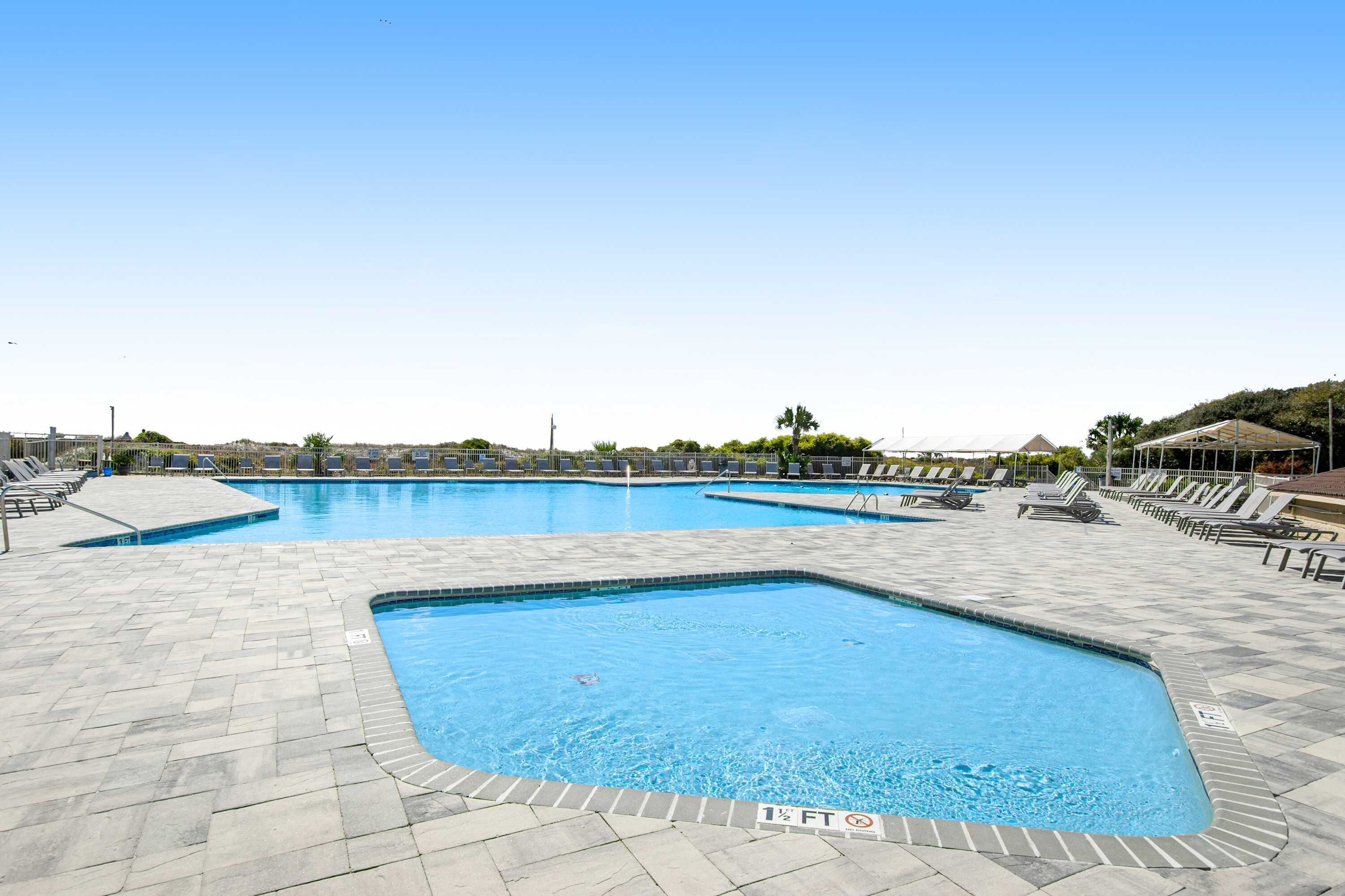 A swimming pool with multiple lanes, sun loungers, and a tiled deck area.
