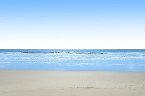 En strand med klar himmel og roligt hav.