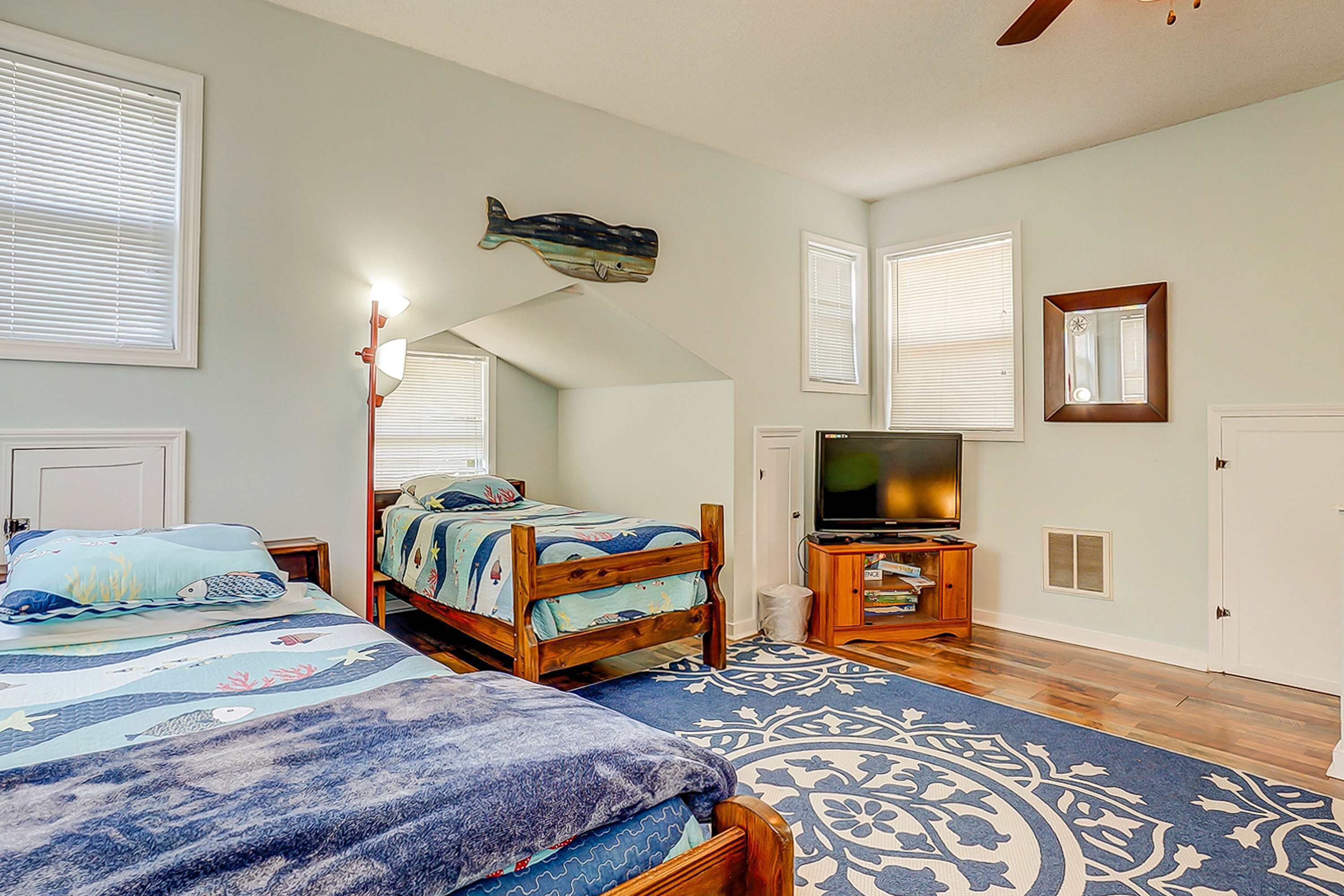 A bedroom with a bunk bed, a television, a wooden cabinet, and a decorative fish wall art piece.
