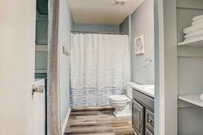 Un baño con cortina de ducha, inodoro y tocador.