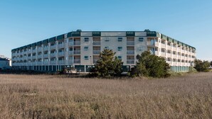 Un edificio de varios pisos con techo plano, varios balcones y un área verde circundante.