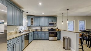 Una cocina con gabinetes azules, electrodomésticos de acero inoxidable y suelo de baldosas.