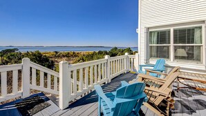 A deck with outdoor seating, a white railing, and a view of the ocean. - Oceanfront house with ocean views & beach access - near dining & golf (Edisto Beach)