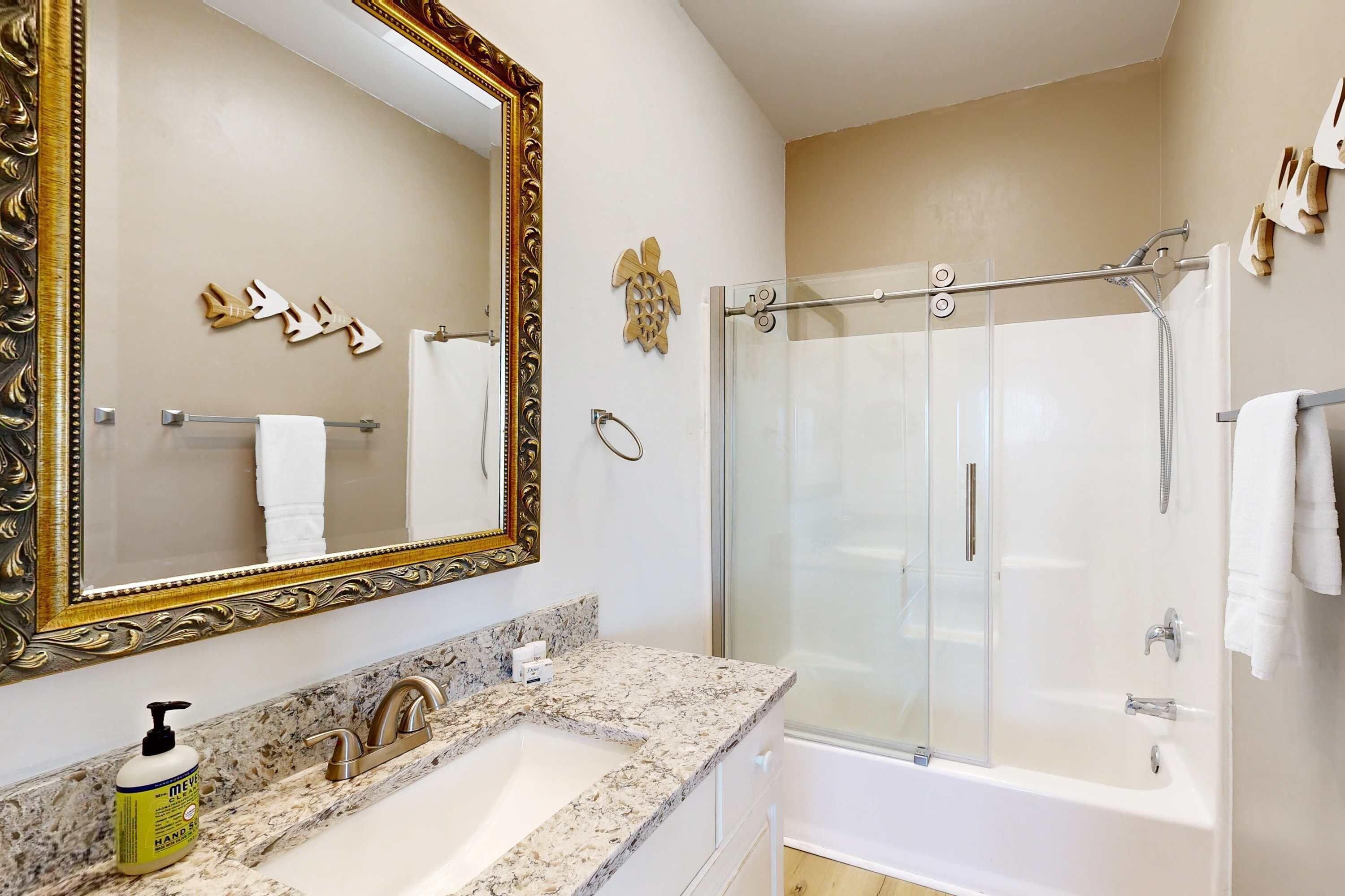 A bathroom with a large mirror, two sinks, a shower, and a bathtub.