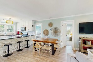 Een moderne keuken met een centraal eiland, barstoelen en een eettafel.