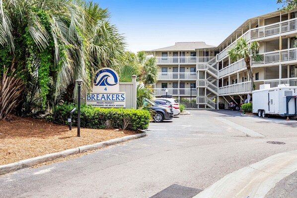 A multi-story building with balconies, a sign for 'BREAKERS' indicating private property, and parked cars. - Beach-view condo in oceanfront complex with outdoor pool, beach access, balcony (Hilton Head)