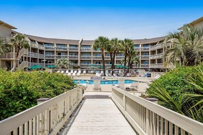 Ein Hotel mit mehreren Balkonen, einem Schwimmbad und üppiger Bepflanzung.
