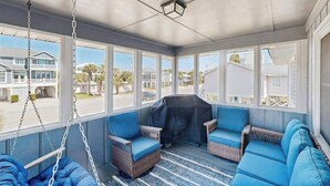 A covered porch with wicker furniture, a swing, and a grill. - Beachfront home w/ Patio, Private W/D, & Free WiFi (Edisto Beach)