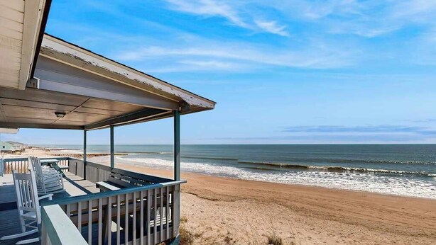 A beach house with a wooden deck, a covered porch, and a view of the ocean. - Beachfront home w/ Patio, Private W/D, & Free WiFi (Edisto Beach)