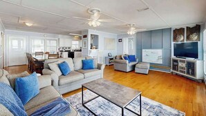 A spacious living room with a fireplace, a television, and a dining area. - Beachfront home w/ Patio, Private W/D, & Free WiFi (Edisto Beach)