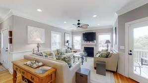 A spacious living room with a fireplace, a ceiling fan, and a television mounted above it. - Fantastic House 2 Blocks From Beach w/Private Pool, Free WiFi, Central AC, & W/D (Edisto Beach)