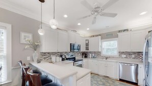 A modern kitchen with white cabinets, a central island, a ceiling fan, recessed lighting, and a patterned backsplash. - Fantastic House 2 Blocks From Beach w/Private Pool, Free WiFi, Central AC, & W/D (Edisto Beach)