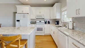 A kitchen with white cabinets, a granite countertop, a built-in oven, a microwave, and a dishwasher. - Newly renovated beachfront house w/Patio, Free WiFi, Private W/D, AC (Edisto Beach)