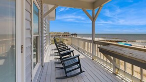 A covered deck with wooden benches, a railing, and a view of the beach and ocean. - Newly renovated beachfront house w/Patio, Free WiFi, Private W/D, AC (Edisto Beach)