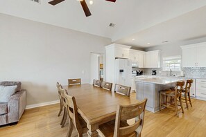 Una cocina moderna con armarios blancos, una mesa de comedor de madera y un ventilador de techo.