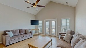 A spacious living room with a sofa, a coffee table, and a ceiling fan. - Newly renovated beachfront house w/Patio, Free WiFi, Private W/D, AC (Edisto Beach)