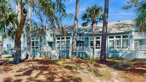 A beachfront property with multiple-story buildings, balconies, and a sandy ground area. - Beautiful home with natural light, lagoon views - Community Hot tub & Pool (Edisto Beach)