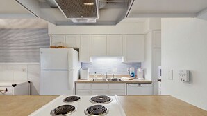 A modern kitchen with white cabinets, a built-in oven, a sink, and a countertop. - Edisto condo with close proximity to beach & restaurants (Edisto Beach)