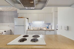 Eine moderne Küche mit weißen Schränken, einem eingebauten Backofen, einer Spüle und einer Arbeitsplatte.