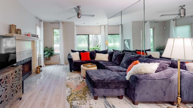 Ein modernes Wohnzimmer mit einem Ecksofa, einem Kamin, einem Fernseher und einem großen Spiegel.