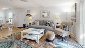 Een moderne woonkamer met een bank, fauteuils, een salontafel en een eethoek met stoelen en een tafel.