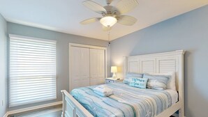 A bedroom with a bed, a ceiling fan, a window with blinds, a nightstand, and a door. - Coastal retreat with fireplace, AC, grill, lagoon views and close to beach (Edisto Beach)