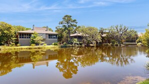A house with a pond in front, surrounded by trees and greenery. - Coastal retreat with fireplace, AC, grill, lagoon views and close to beach (Edisto Beach)