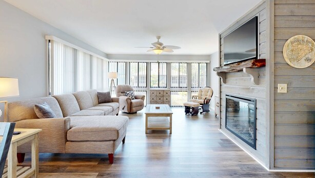 A spacious living room with a sofa, chairs, a coffee table, a fireplace, and a television. - Coastal retreat with fireplace, AC, grill, lagoon views and close to beach (Edisto Beach)