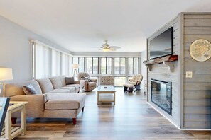 A spacious living room with a sofa, chairs, a coffee table, a fireplace, and a television. - Coastal retreat with fireplace, AC, grill, lagoon views and close to beach (Edisto Beach)