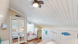 Ein Schlafzimmer mit Bett, Deckenventilator, Kleiderschrank und Spiegel.