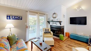 Ein Wohnzimmer mit Sofa, Sessel, Tisch, Kamin und Fernseher.