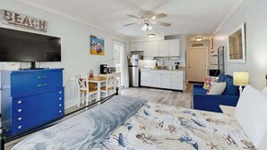 A bedroom with a bed, a desk, a kitchenette, and a bathroom. - Charming & sun-filled studio with great patio & W/D - close to beach (Edisto Beach)