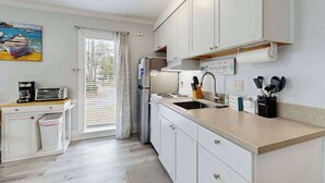 A compact kitchen with white cabinets, a built-in oven, a sink, and a coffee maker. - Charming & sun-filled studio with great patio & W/D - close to beach (Edisto Beach)