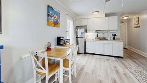 A compact kitchen with white cabinets, a dining table with chairs, a ceiling fan, and a small island with a sink. - Charming & sun-filled studio with great patio & W/D - close to beach (Edisto Beach)